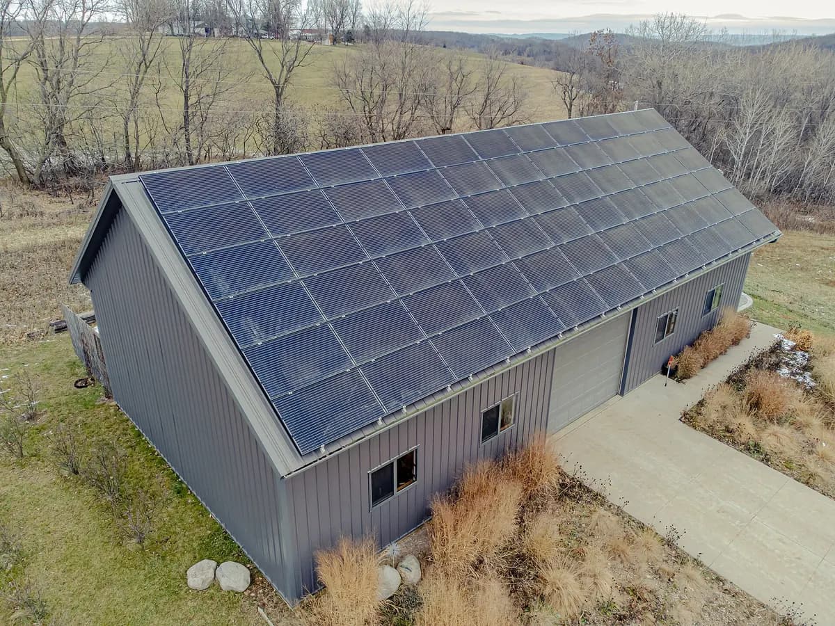Aerial view of a grey metal-clad building with its whole south-facing roof covered in dark solar panels